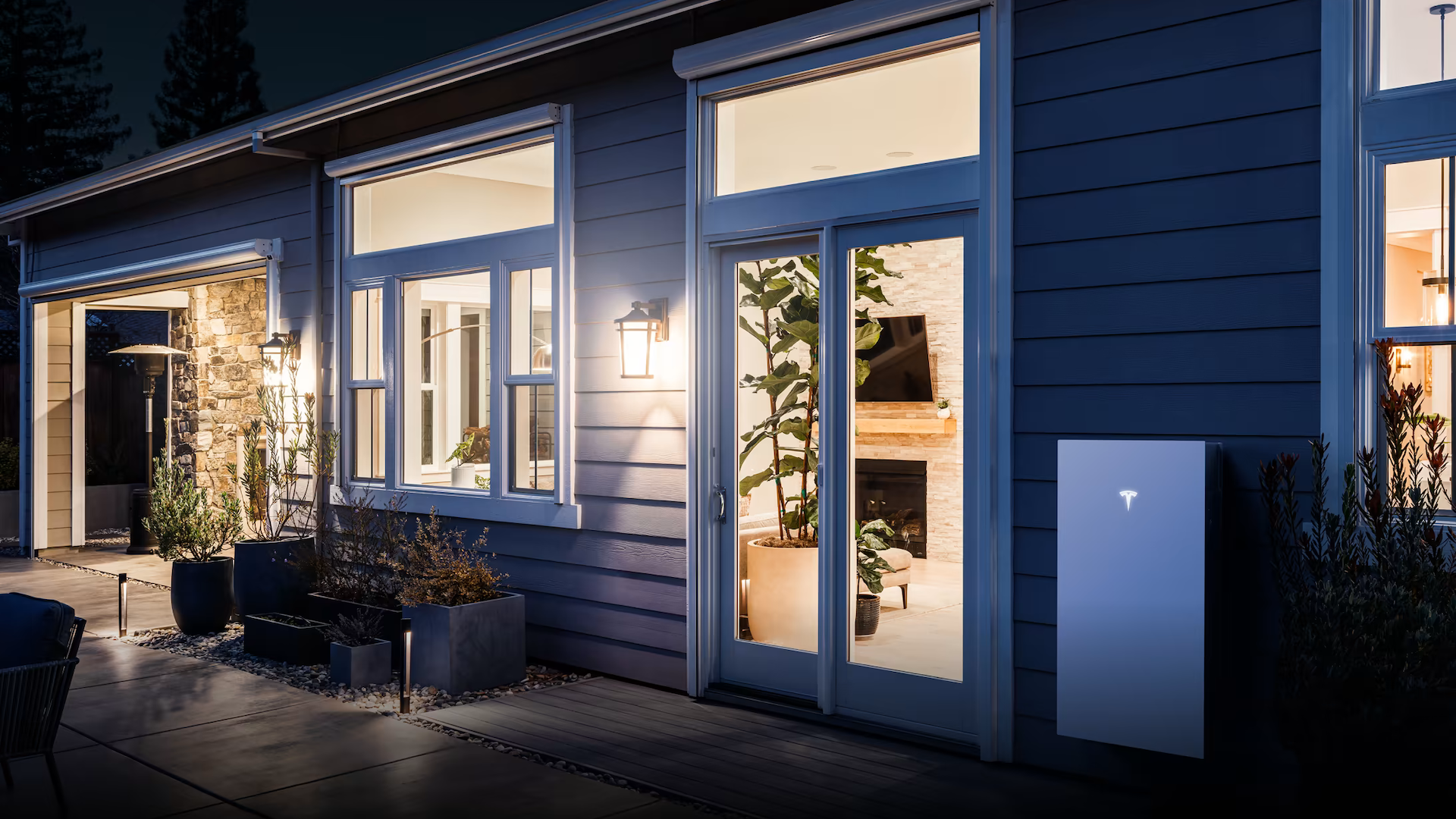 Tesla Powerwall 3 at Dusk with House lights on in the background